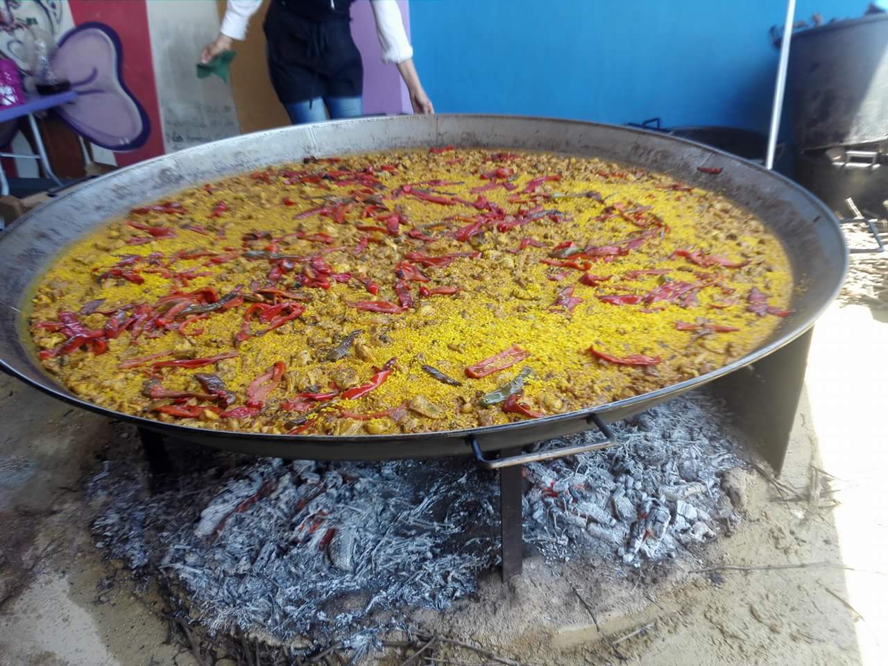 Paella gigante cocinándose a la leña en un evento